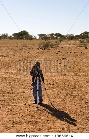 African American barn med et stativ og kamera i Kalahari, Botswana.