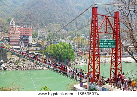 INDIA, LAXMAN JHULA - APRIL 13, 2017: People walking on the suspension bridge at the river Ganges in Laxman Jhula on 13th april 2017