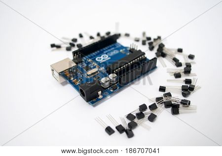 Arduino and around transistors lined up on a white background