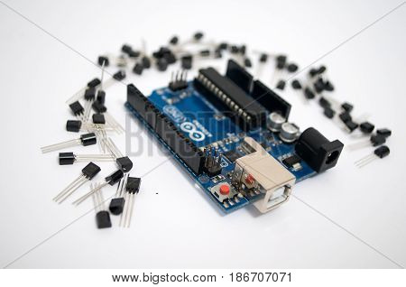 Arduino and around transistors lined up on a white background