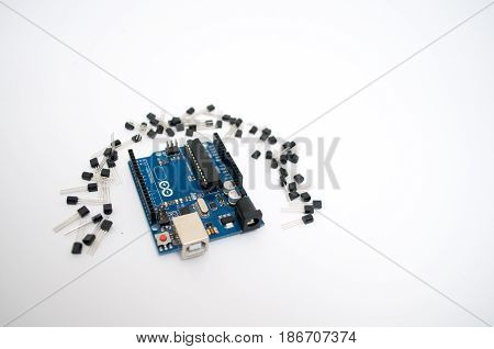 Arduino and around transistors lined up on a white background