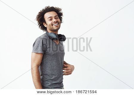 Young cheerful african man with headphones smiling looking at camera over white background.