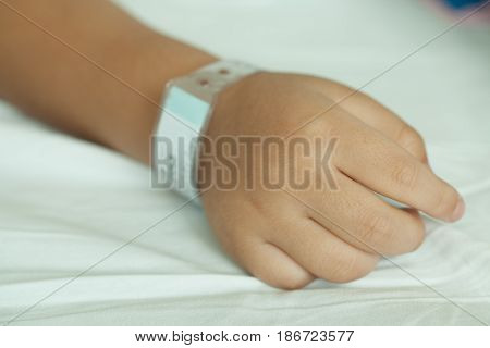 Hands of littel boy and Wristband barcode in hospital bed