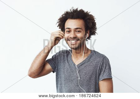 Happy african man putting out headphone lookig at camera smiling. White background. Copy space.