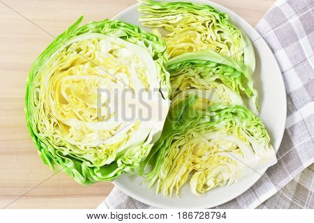 fresh green cut head of cabbage on ceramic gray plate, wooden and natural material background