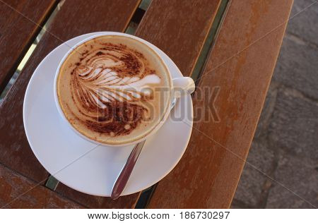 cup of cappuccino on an old wood table outdoors