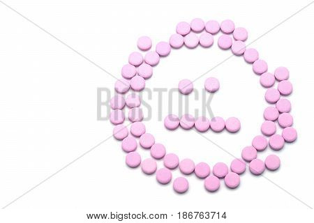 Unhappy face of pink pills on white background. Tablets of drug for asthma treatment