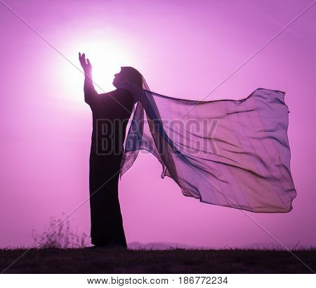 Woman with her hands up on sunset