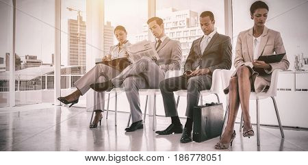 Well dressed business people sitting together in waiting room at office