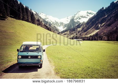 OBERSTDORF, BAVARIA, GERMANY - MAY 10, 2017: Vintage blue and white VW Bully camping car driving on mountain valley road in Trettachtal valley, Allgauer Alps.