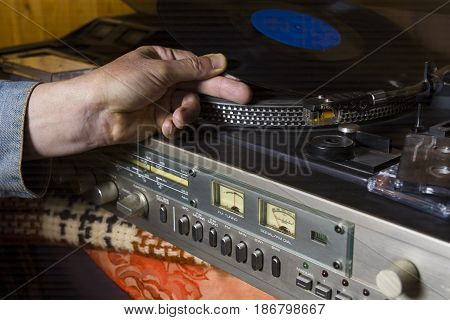 A DJ hand with vinyl record closeup indoor shot concept of a prty in a house