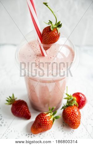 Strawberry-banana smoothie with milk or yoghurt. Healthy summer smoothies to go in a plastic cup