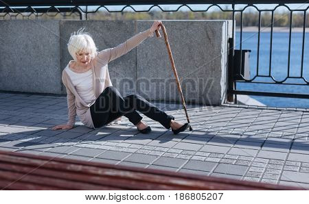 Do not be indifferent. Humble upset confused woman using a stick and lifting on the toes while falling down