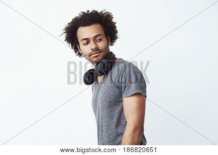 Portrait of young handsome african man with headphones over white background. Copy space.