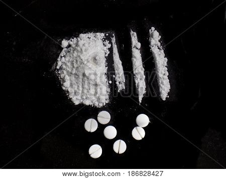Cocaine drug powder pile and lines and pills on black background