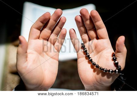 Muslim man hands holding rosary with quraan
