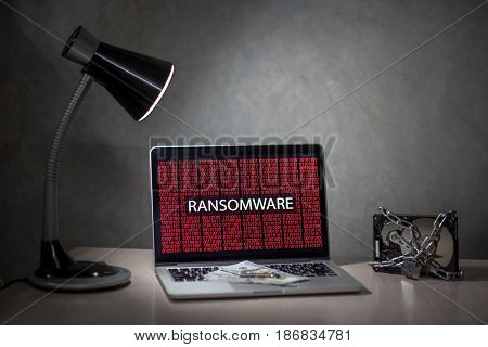 laptop computer screen with ransomware attack alert in red digital binary background with hard disk drive lock Cyber attack concept