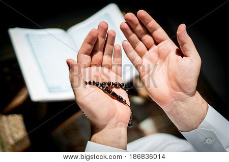 Muslim man hands holding rosary with quraan