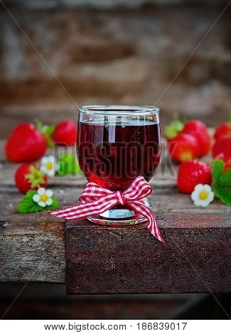 homemade strawberry liqueur, fresh strawberries and flowers on wooden background