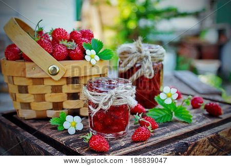 jam from wild strawberries in a jar and fresh flowers and berries