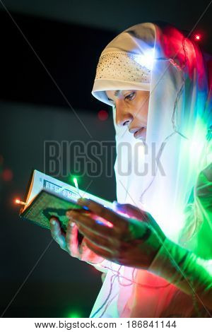 Muslim woman praying in dark room with nice lights around her