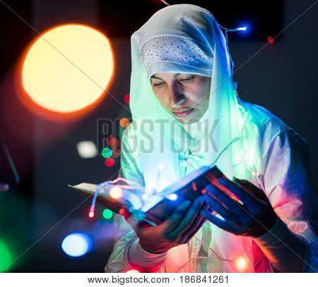 Muslim woman praying in dark room with nice lights around her