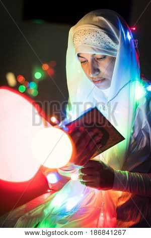 Muslim woman praying in dark room with nice lights around her