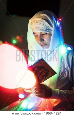 Muslim woman praying in dark room with nice lights around her