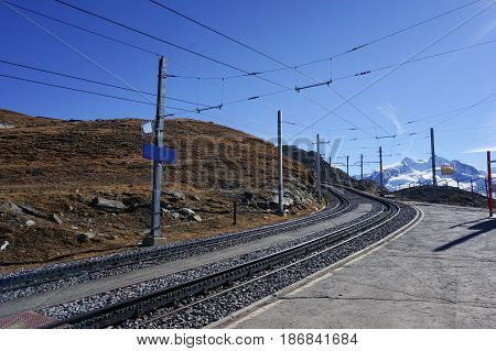 Beautiful scenic train railway transportation on alp with snow mountain in daylight Switzerland.