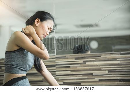 Asian woman having neck pain after workout at the gym.