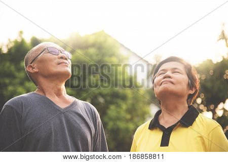 Happiness Couple Asian senior man and woman relaxing and breathing fresh air at park with sunlight. copy space. Plants Natural background.