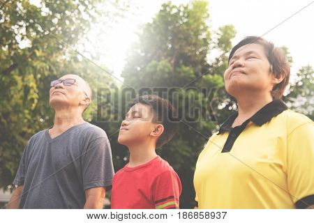 Happiness Group Asian family relaxing and breathing fresh air at park with sunlight. copy space. Plants Natural background.