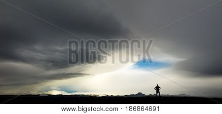 Silhouette of man watching big stormy clouds and the force of nature. Extreme weather in the Highland of Iceland with a blue eye of the storm.