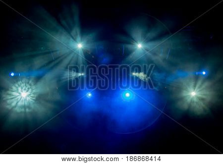 The blue light from the spotlights through the smoke in the theatre during the performance. Lighting equipment.