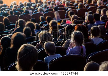 People, children, adults, parents in the theater watching the performance.