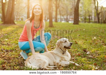 Woman with labrador on walk in park on green lawn