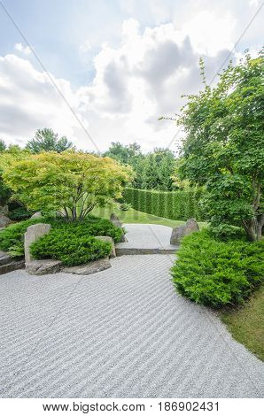 japanese zen garden with cloudy sky and green trees