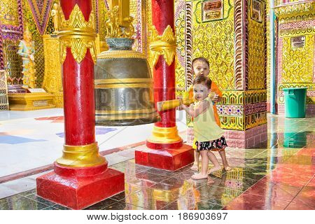 MANDALAY,MYANMAR - MARC 7, 2017: Myanmar children ringing the bell at  Su Taung Pyi Pagoda on top of Mandalay Hill on March 7, 2017, in Mandalay, Myanmar (Burma)
