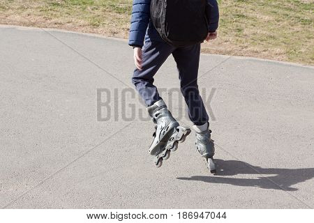 the person rides roller skates in the park in clear summer day