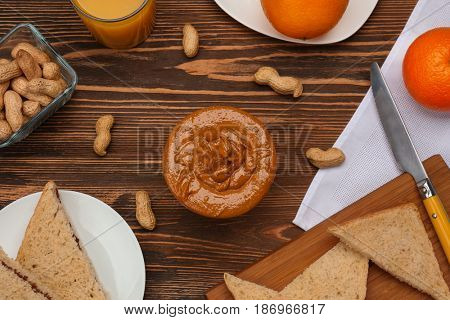 Delicious peanut butter in bowl with different meal on wooden table