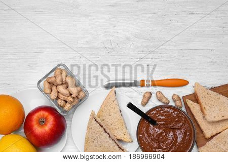 Delicious peanut butter in bowl with different meal on wooden table