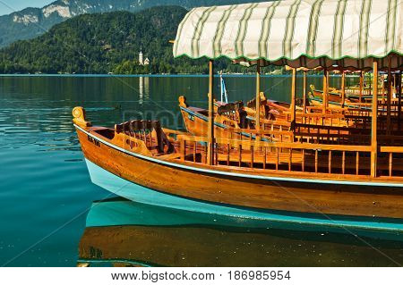 Pletna gondolas at lake Bled with a church on a small island in Slovenian alps, Slovenia