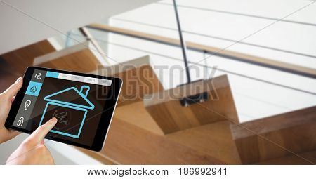 Digital composite of Hands using smart home app on tablet PC with staircase in background