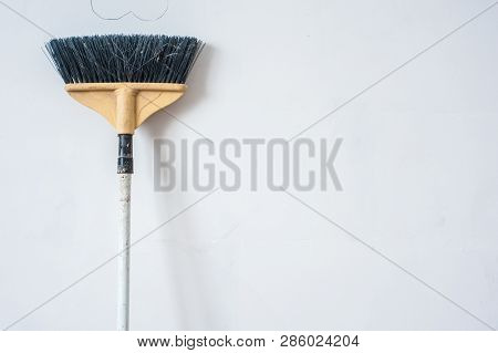 Close Up Of Red Black Broom On White Background. Cleanliness Concept. Copy Space.