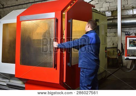 The Worker In Blue Workwear, The Operator Of The Cnc Machine, Oversees The Process And Controls It. 