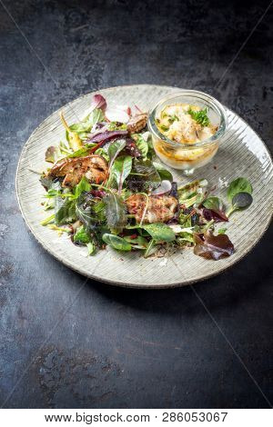 Backed Norwegian skrei cod fish filet with fresh lettuce, mushroom and parmesan as closeup on a modern design plate 