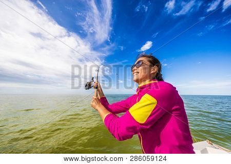 Fishing woman having fun learning to fish throwing casting line on ocean. Tourist on boat excursion.