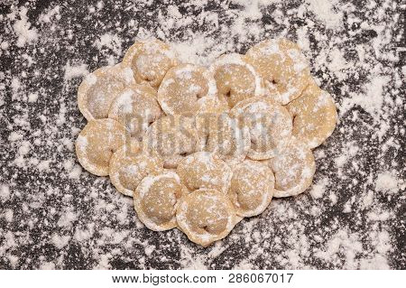 Raw Yellow Dumplings, Flouted Lie In The Shape Of A Heart On A Wooden Brown Board