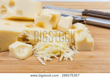 Partly Sliced And Grated Swiss-type Cheese On A Bamboo Wooden Cutting Board Close-up At Selective Fo
