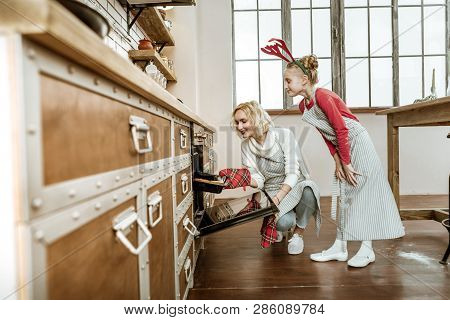 Short-haired Beaming Woman Using Special Glove For Putting Hot Pan